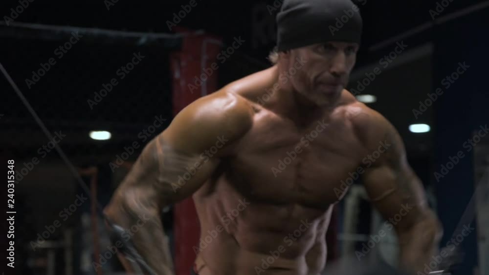 Adult male athlete with tattoos on his arms exercising in the gym. Adult male athlete with tattoos on his arms exercising in the gym.