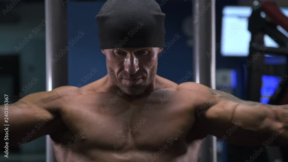 Adult male athlete with tattoos on his arms exercising in the gym. Adult male athlete with tattoos on his arms exercising in the gym.