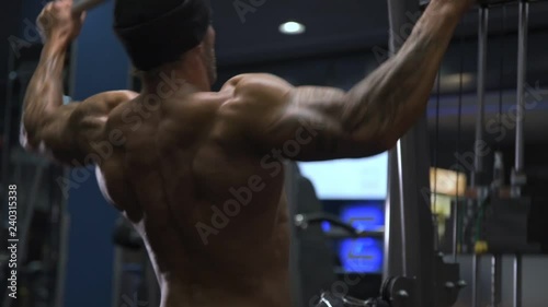 Adult male athlete with tattoos on his arms exercising in the gym.