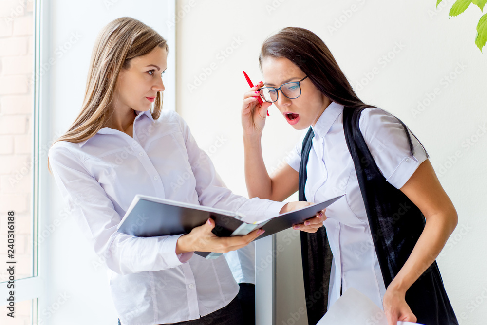 two businesswomen telling gossip in an office two businesswomen telling gossip in an office