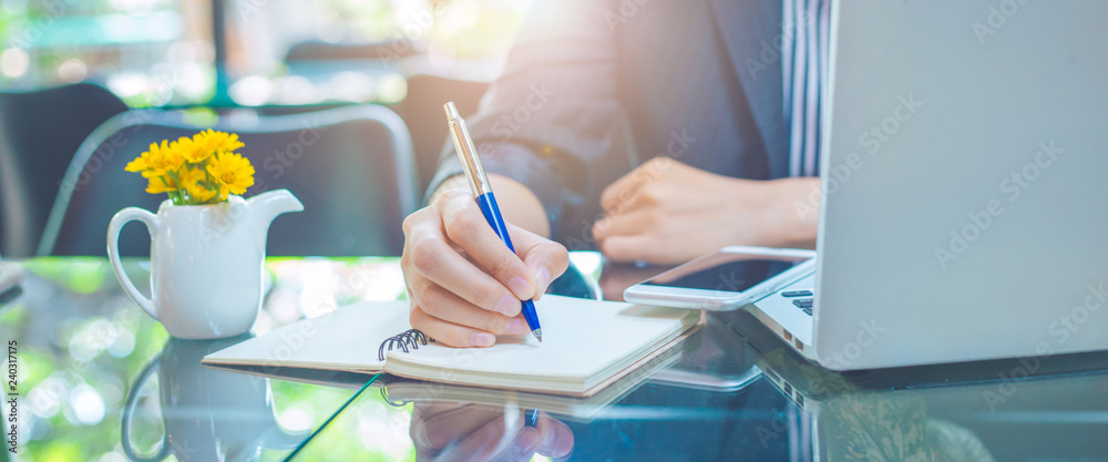 Business woman writing on a notebook.with a pen in the office