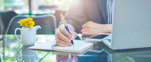 Business woman writing on a notebook.with a pen in the office