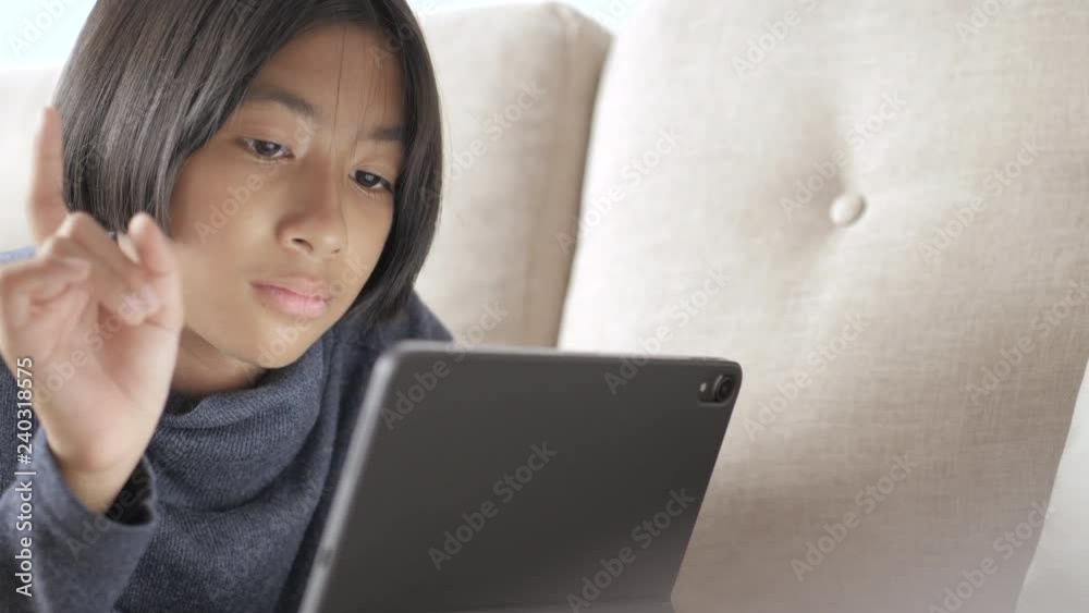Asian girl using tablet computers for education on sofa Asian girl using tablet computers for education on sofa