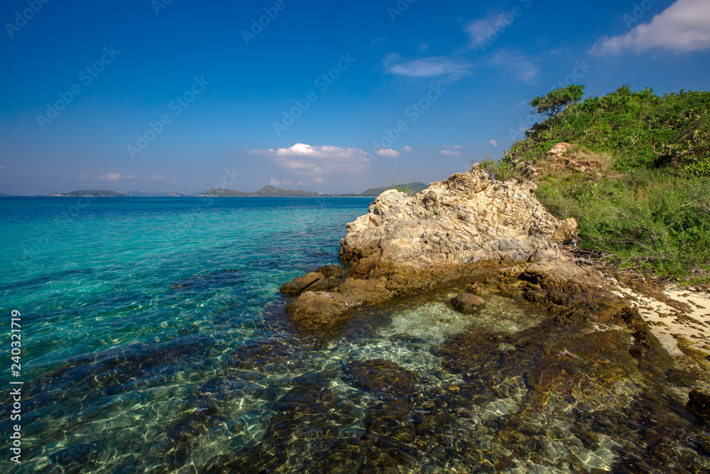 The background of the clear water of the sea, clearly visible sand and rocks, blue sky wallpaper With natural beauty