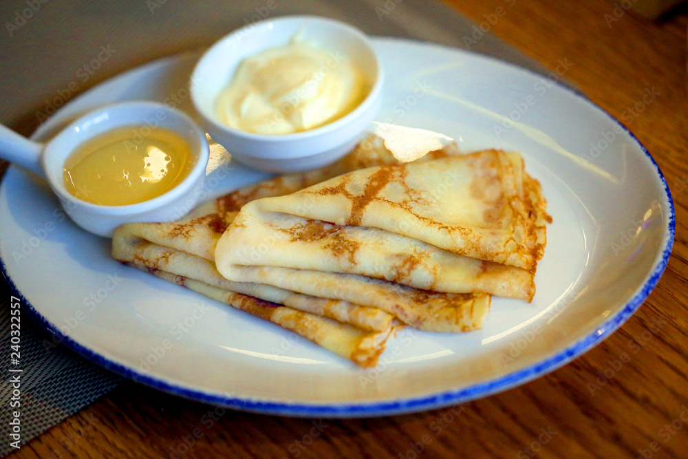 Macro photo of delicious pancakes with honey and sour cream on a white plate Macro photo of delicious pancakes with honey and sour cream on a white plate