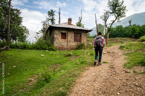 A person walking up the hill to his home on a dirt road in a village in Kashmir