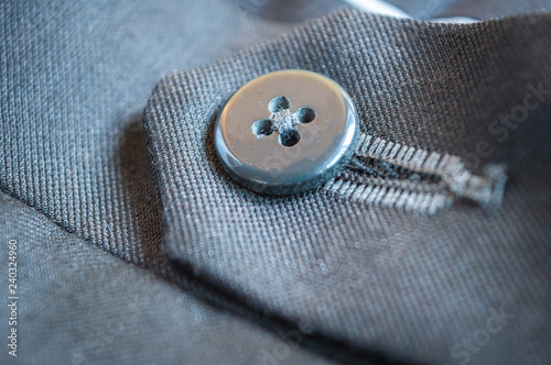 Close up of the button of a grey formal pant