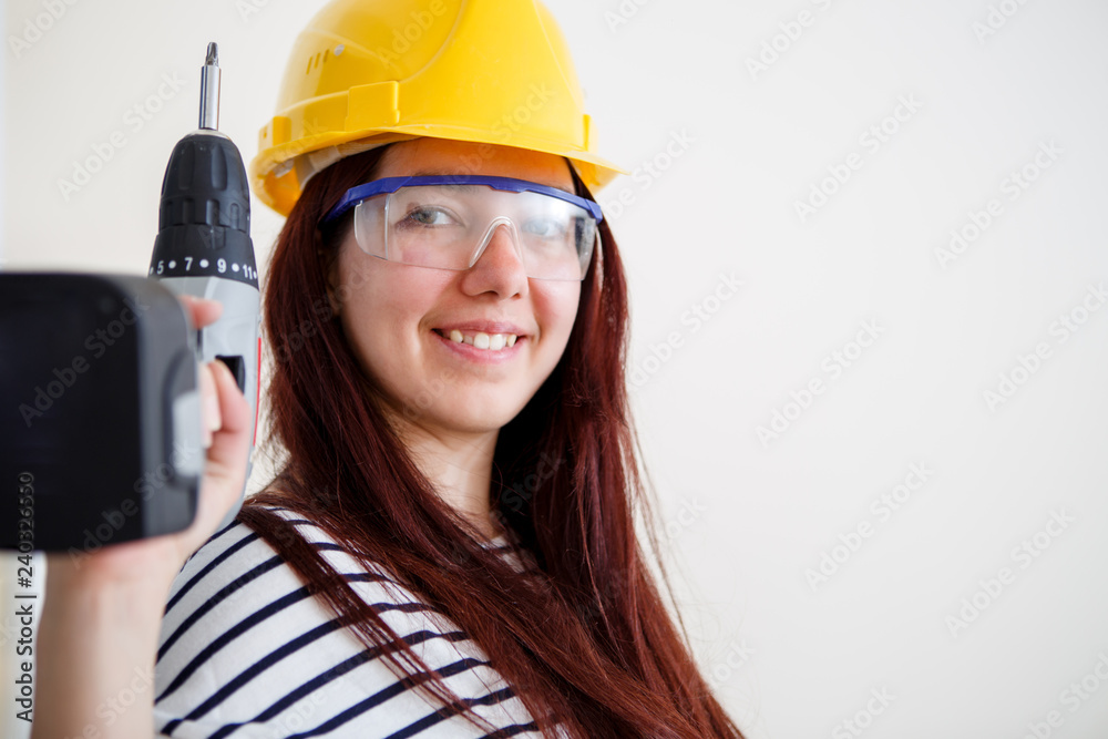 Image of woman in yellow helmet with drill in hand Image of woman in yellow helmet with drill in hand