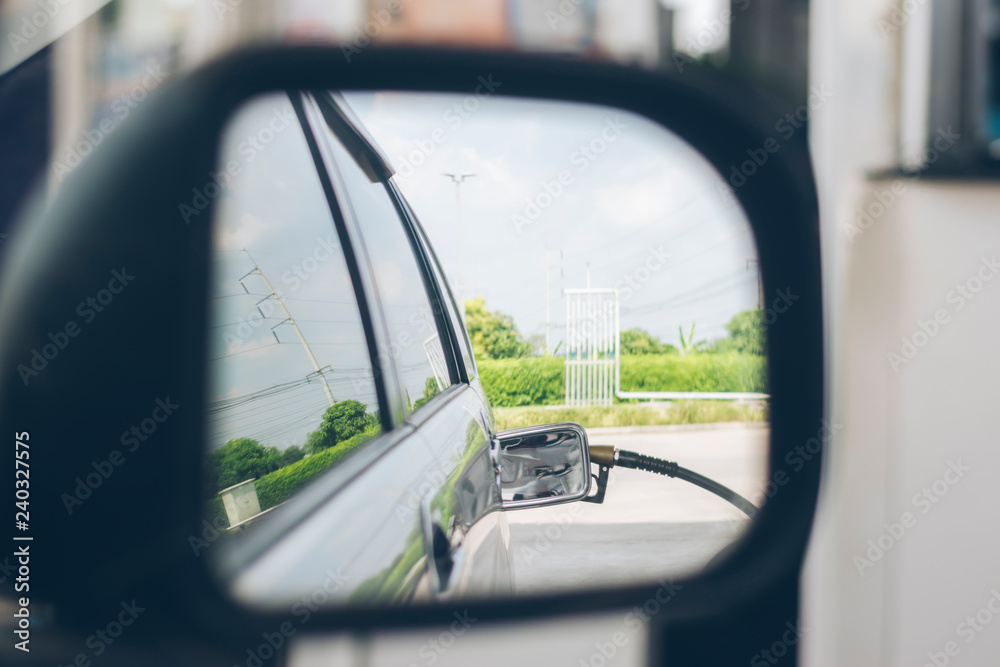 Looking through the rear view mirror. The car is refueling. Looking through the rear view mirror. The car is refueling.