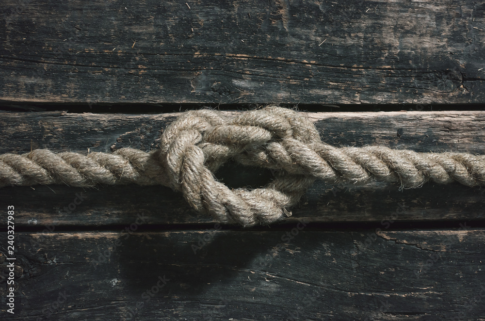 Fototapeta premium Rope knot on the wooden surface background.