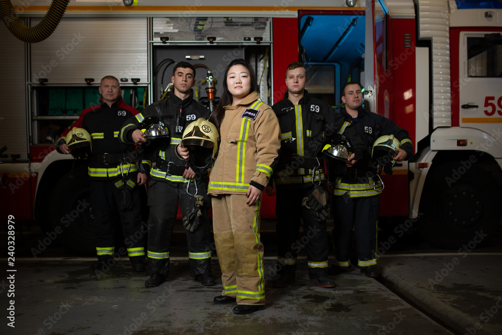 Image of four male and female firefighters on background of fire truck Image of four male and female firefighters on background of fire truck