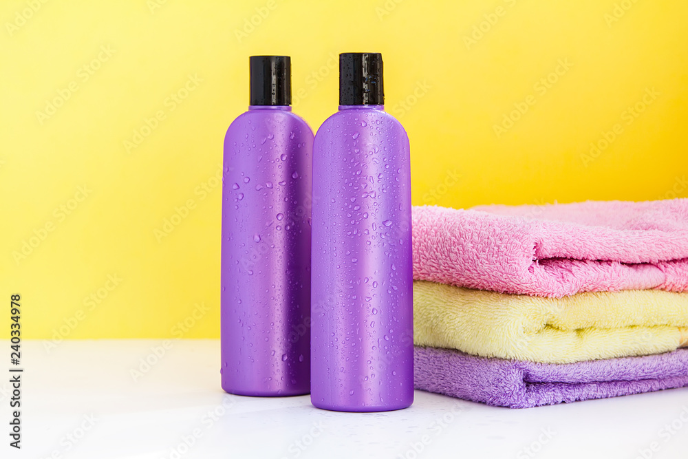 two purple cosmetic bottles and three towels on a lilac background two purple cosmetic bottles and three towels on a lilac background