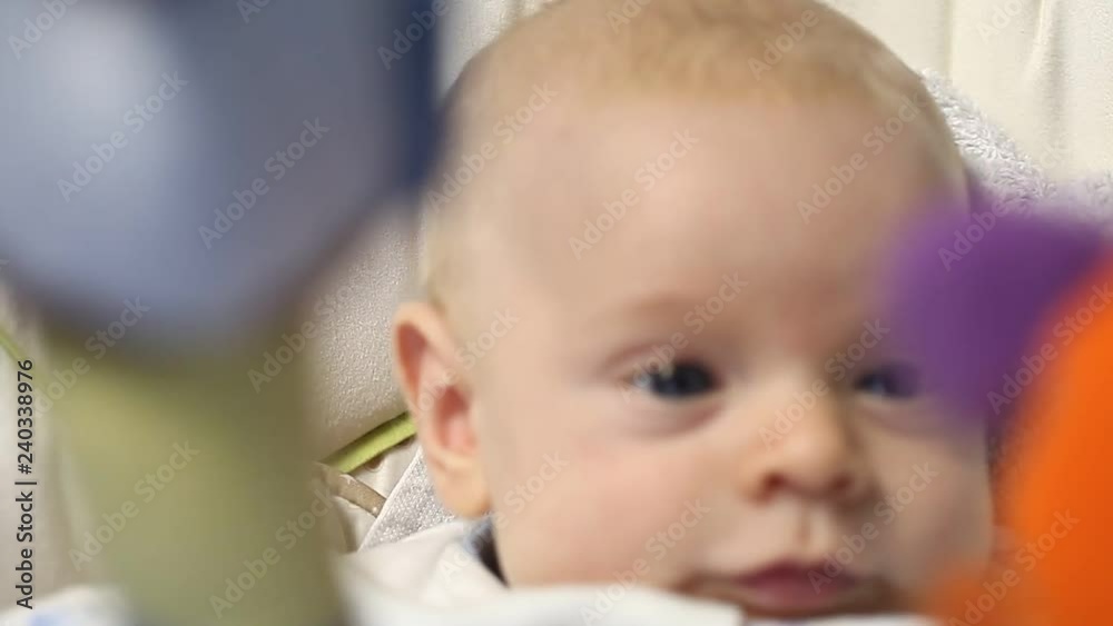 Newborn funny baby lies playing toys in the cradle against the Christmas tree Newborn funny baby lies playing toys in the cradle against the Christmas tree