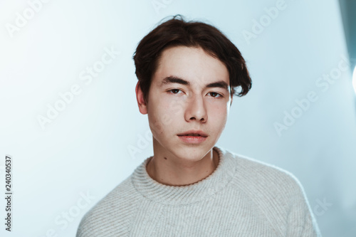 Studio portrait young man in grey sweater on white background