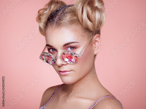 Portrait of Beautiful young Woman with Colored Glasses. Beauty Fashion. Perfect Make-up. Colorful Decoration. Hair Curled into a Bun photo