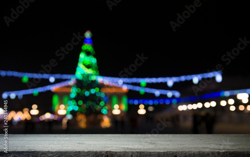 blurred wall background with xmas tree of few colors lights and shabby table