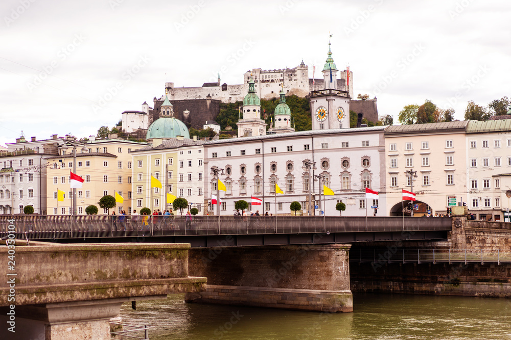 Naklejka premium Salzburg city with it's castle on the hill and old town with river on foreground.