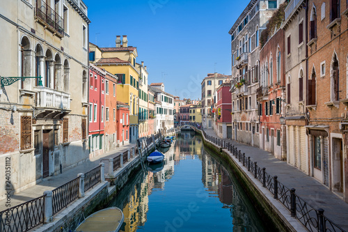 Sunny view of empty channel and street of Venice old town.