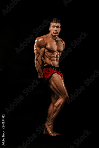 Brutal strong muscular bodybuilder athlete man pumping up muscles on black background. Workout bodybuilding concept. Copy space for sport nutrition ads.