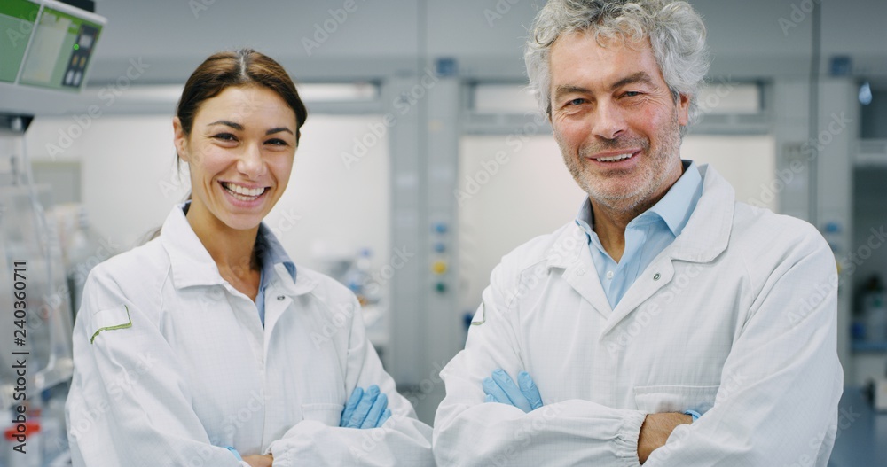 Obraz premium Portrait of two smiling scientists wearing protection glasses satisfied with a great results of completed research in laboratory. Concept: research,biochemistry, pharmaceutical medicine