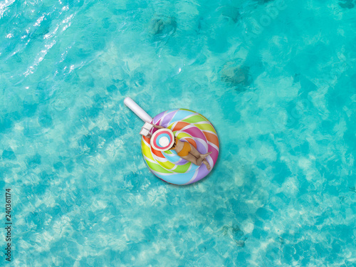 Aerial top view of woman bikini enjoy with reading a book, playing, laying in inflatable swimming tube in the sea water, enjoy feel comfortable in long holidays vacation in summertime at the sea.