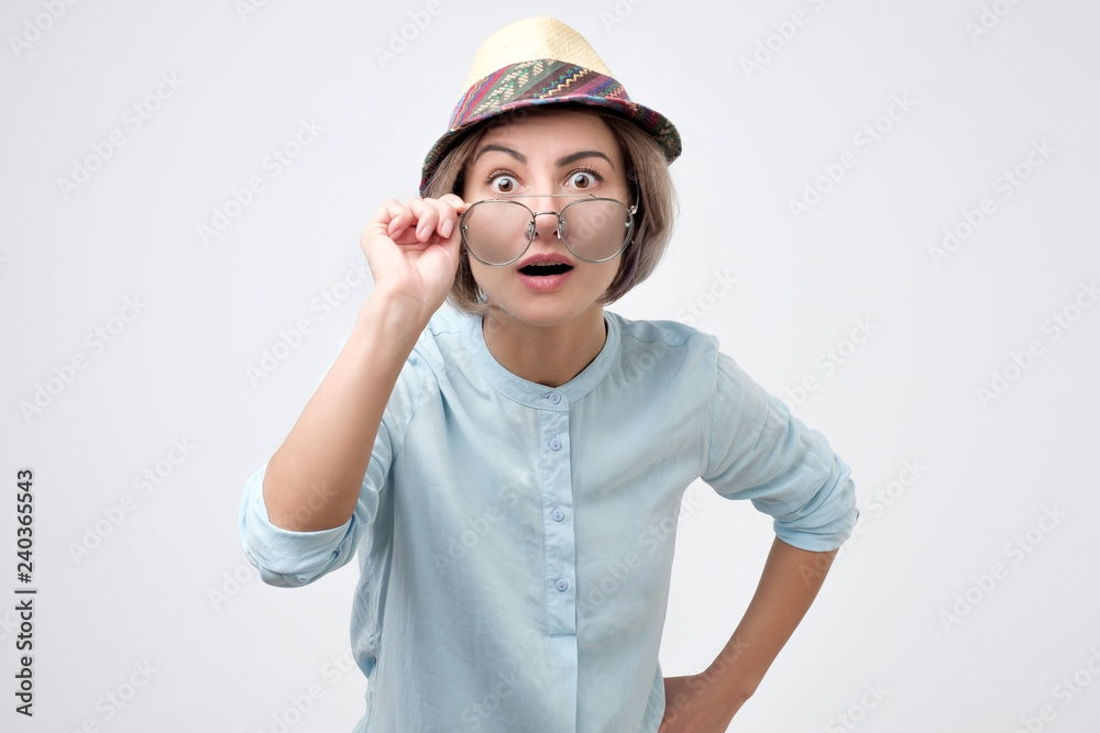 Surprised young woman in hat and glasses with open mouth can not believe her eyes. Surprised young woman in hat and glasses with open mouth can not believe her eyes.