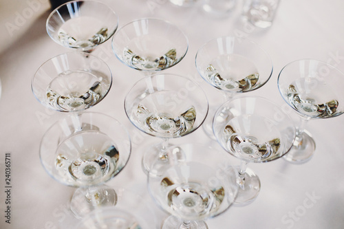 Martini row on table party at wedding reception. Martini drinks in crystal glasses at alcohol bar. Christmas and New Year feast. Celebrations and party concept.