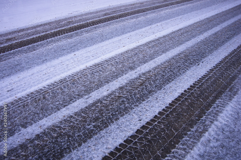 Fototapeta premium Abstract background of car tracks on snow-covered road. Snow traces of the wheel of the car. Trace of the wheels on the snow as a background