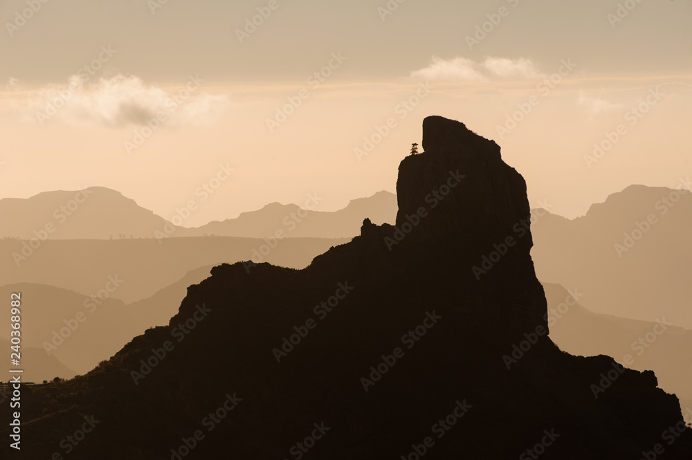 GRAN CANARIA, SPAIN - NOVEMBER 6, 2018: Top point of Roque Nublo mountain under the yellow sky with clouds