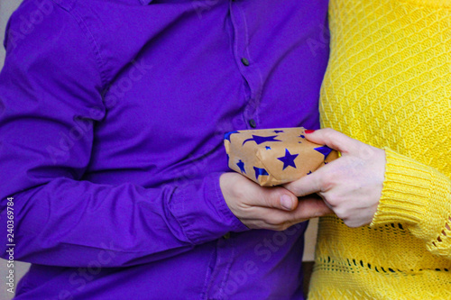 the moment of giving a gift of one person to another. in the frame of a hand with a gift. purple and yellow color