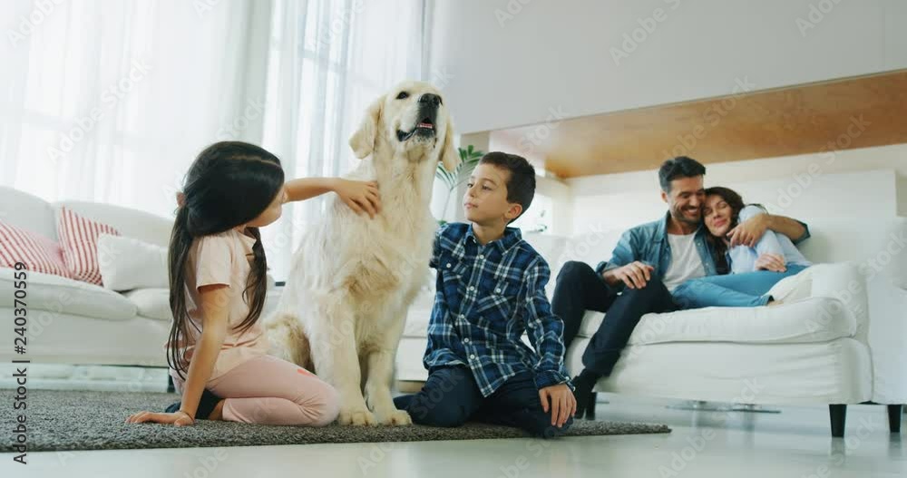Portrait of happy family with a dog having fun together in living room in slow motion. Shot with RED camera in 8K. Concept of happy family, parenthood, love for animals