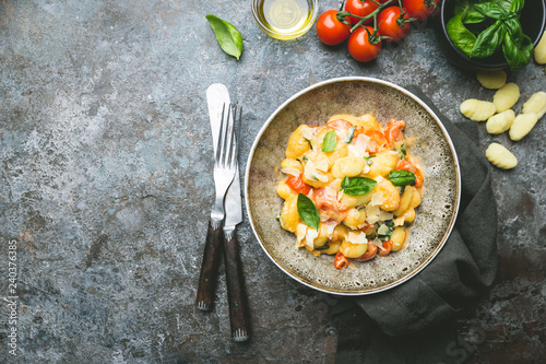 Homemade italian gnocchi with tomato, garlic, basil and mozzarella cheese on stone background. Top view. Copy space. photo