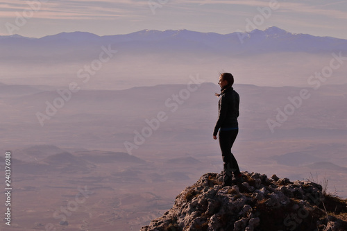 GIRL LOOKING AT A GREAT VALLEY FROM THE SUMMIT OF A MOUNTAIN © JIT