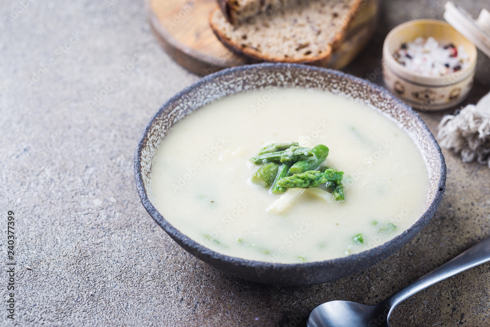 Fresh asparagus cream soup in a bowl over gray stone table Fresh asparagus cream soup in a bowl over gray stone table
