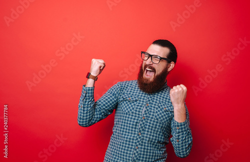Photo of bearded man in glasses, screaming and holding fists up, celebrating victory photo
