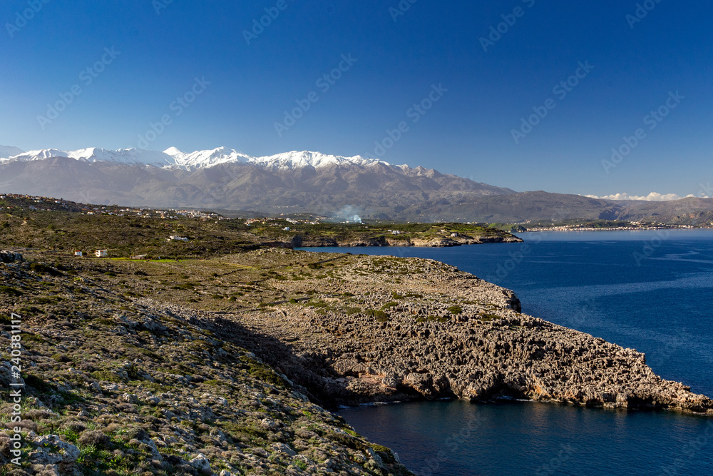 Traditional village near the sea with snowy mountains and blue sky in background. Crete Gre
