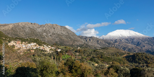 Traditional village in mountain with snowy mountains and blue sky in background. Crete Greece.