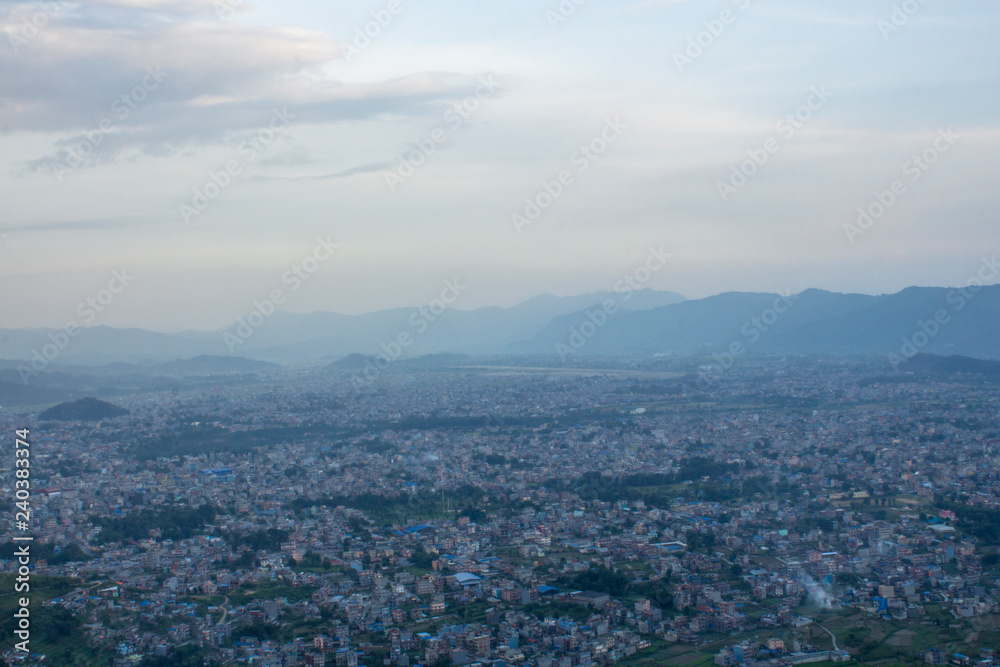 view of the huge city valley on the background of the silhouette of the mountains in the evening under heavy sky