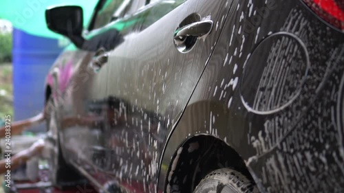 Slow motion worker in car wash service used sponge to cleaning and washing a black car.