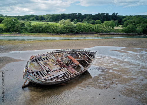 An old wooden fishing boat lay on its side at low tide. photo