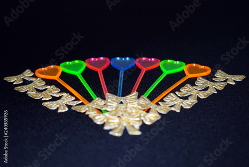 Colorful hearts and gold butterflies on a black background. Valentine's day.  Cocktail decorations. Plastic skewers in the shape of a heart. photo