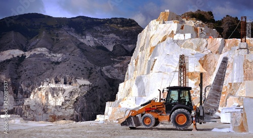 Extraction and processing of precious white marble Statuario, tractor with a giant saw used for cutting marble blocks in a quarry