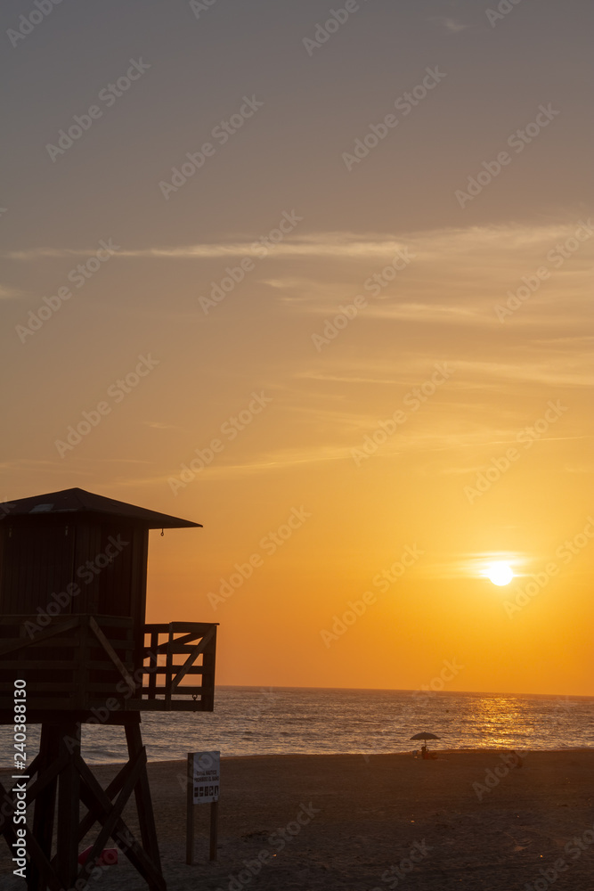The sun setting behind a lifeguard tower on a beach in Rota, Spain.