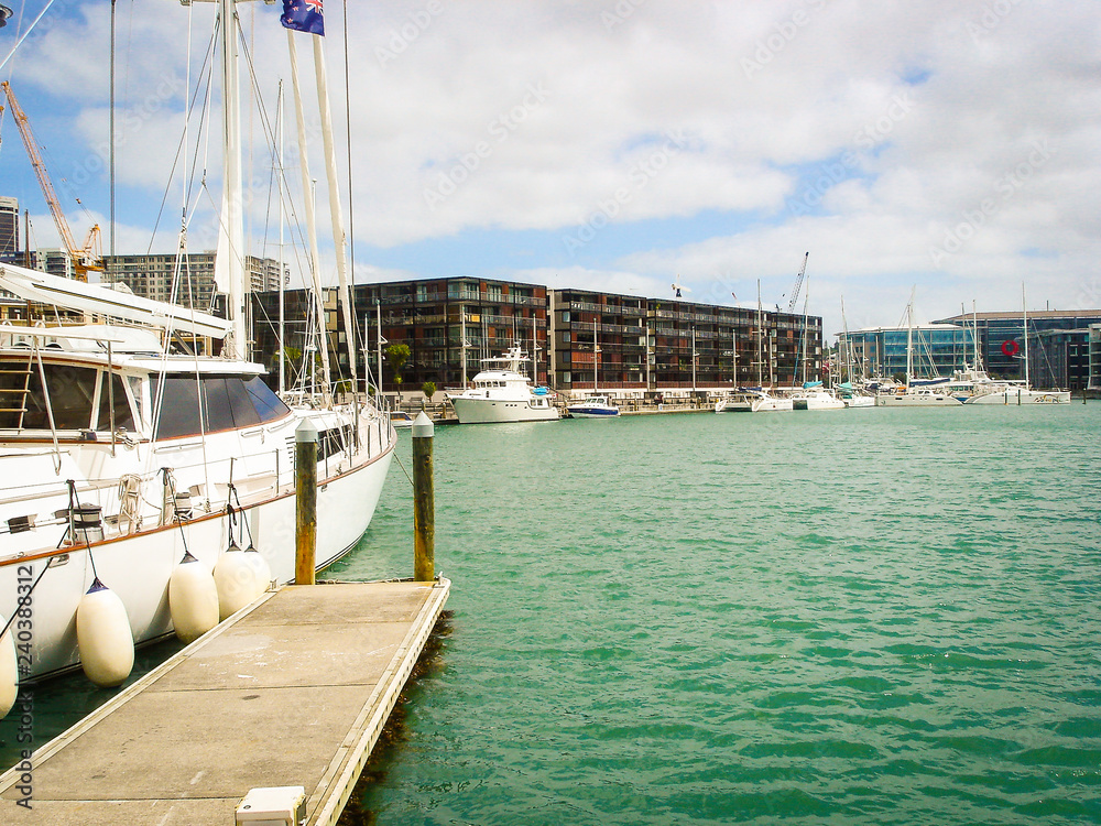 A pier with a sailboat and turquoise water in the harbor of New Zealand
