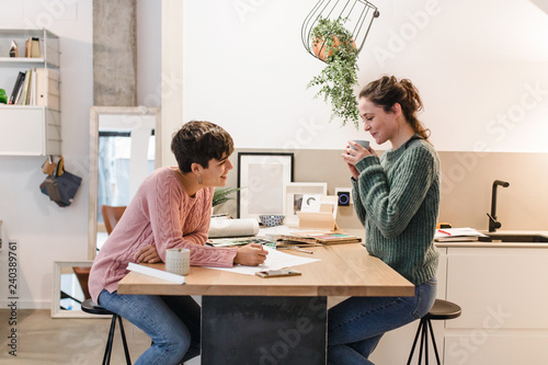 Side view of two women interior designers discussing about blueprints