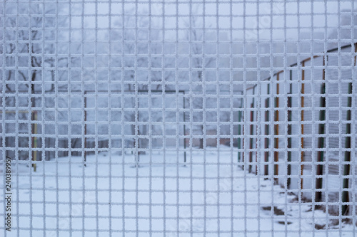 Snowed sport yard behind frosty metal grid net in winter photo