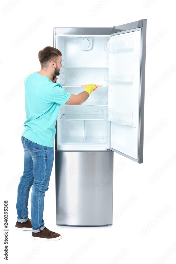 Young man cleaning refrigerator with rag on white background Young man cleaning refrigerator with rag on white background