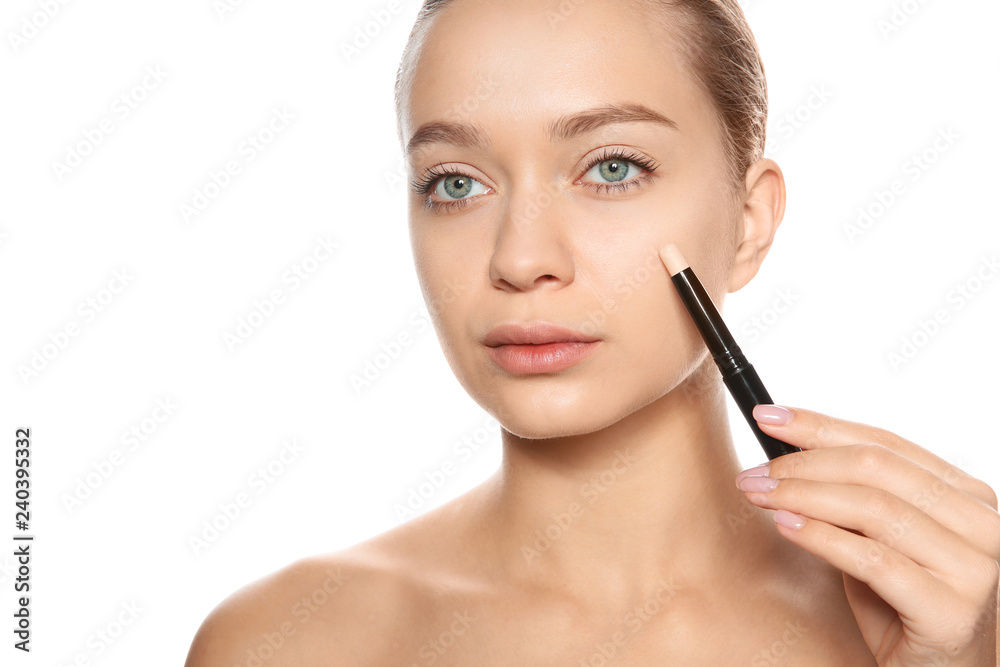 Young woman applying foundation on her face against white background Young woman applying foundation on her face against white background