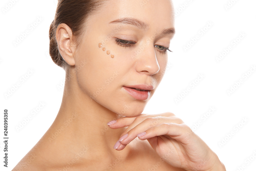 Portrait of young woman with liquid foundation on her face against white background