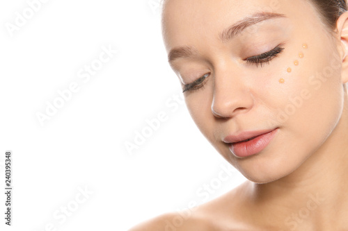 Portrait of young woman with liquid foundation on her face against white background